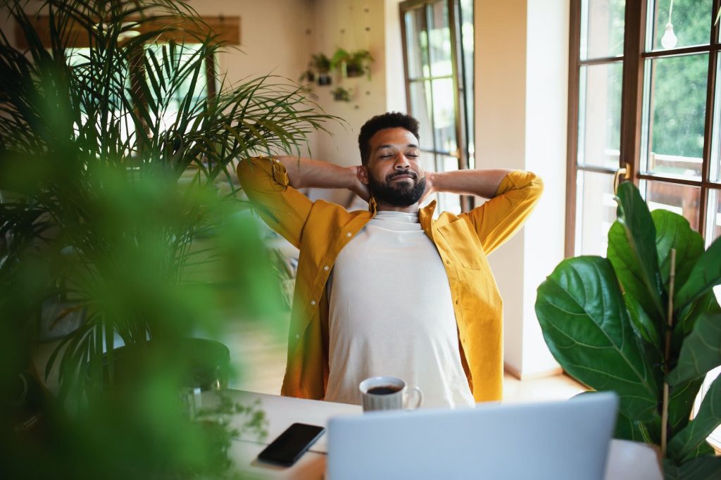 A young man working from home. He has the computer on while connected in a TŌGŌ intranet.